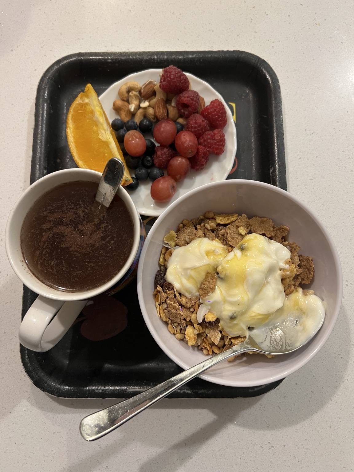 Breakfast with fruit, nuts, yoghurt cereal and a warm drink