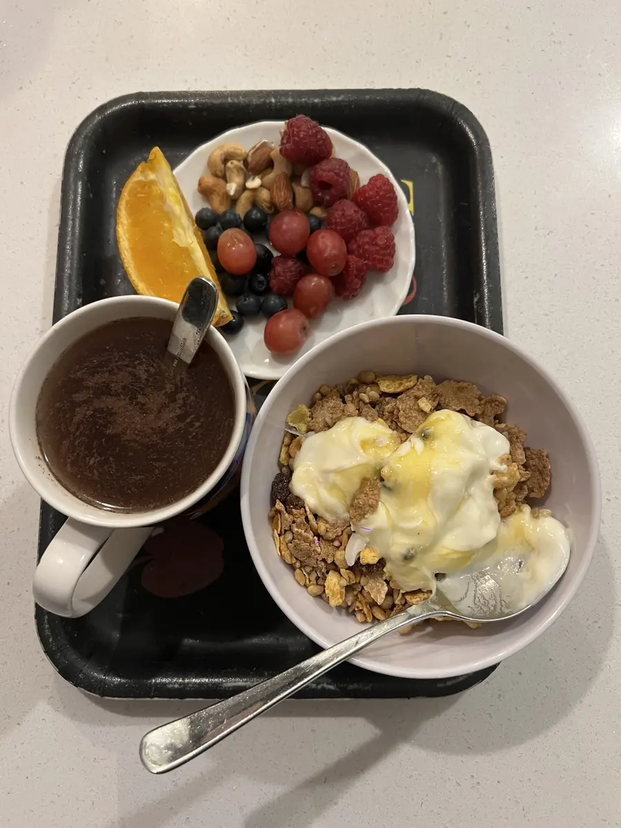 Breakfast with fruit, nuts, yoghurt cereal and a warm drink