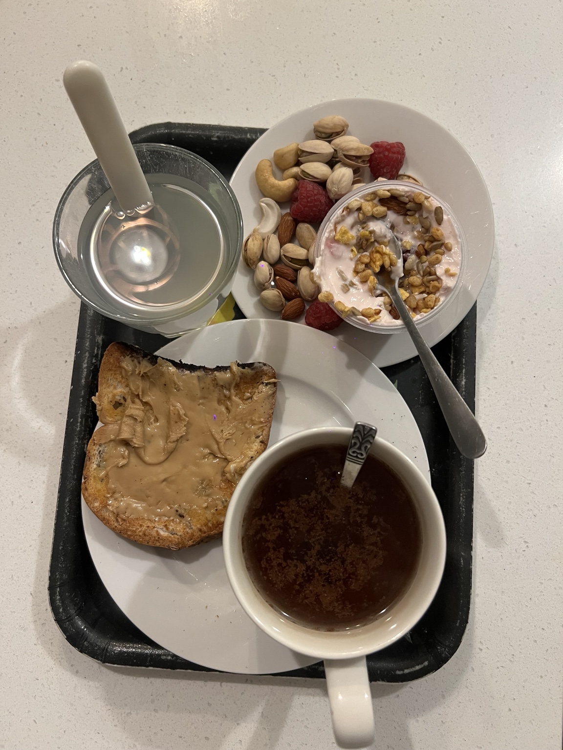 Breakfast with toast, yoghurt, nuts, berries and warm drinks