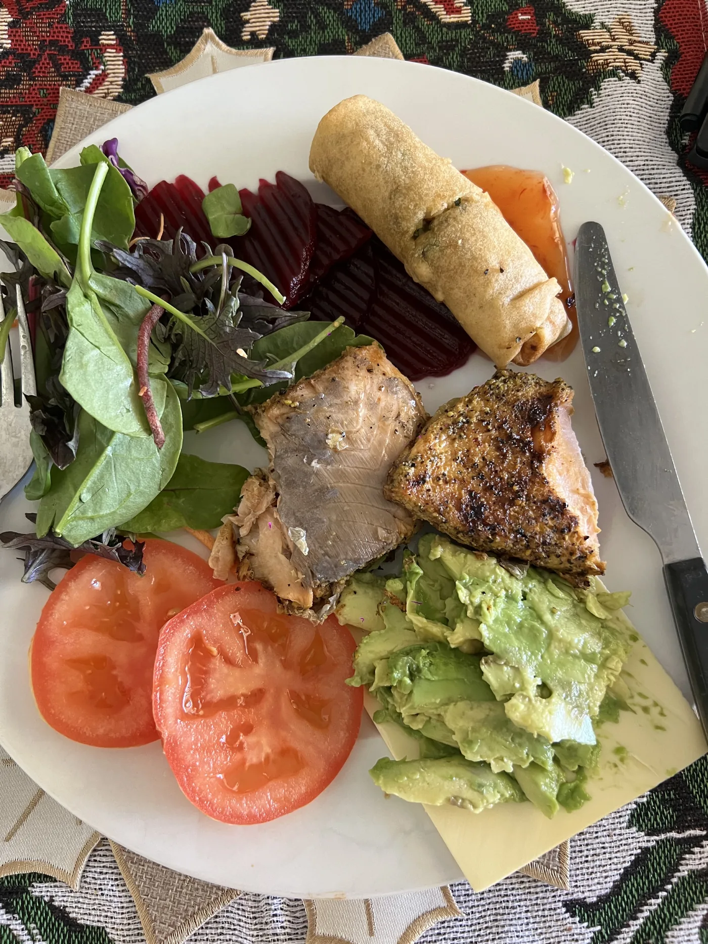 Plate with salmon, avocado, tomatoes, salad, beetroot and spring roll
