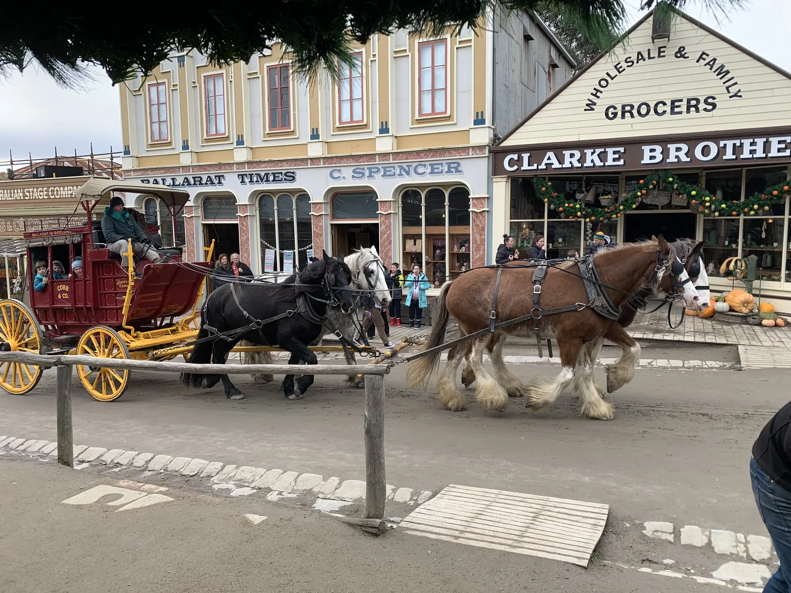 Clydesdales pulling a red coach on Main Street at Sovereign Hill
