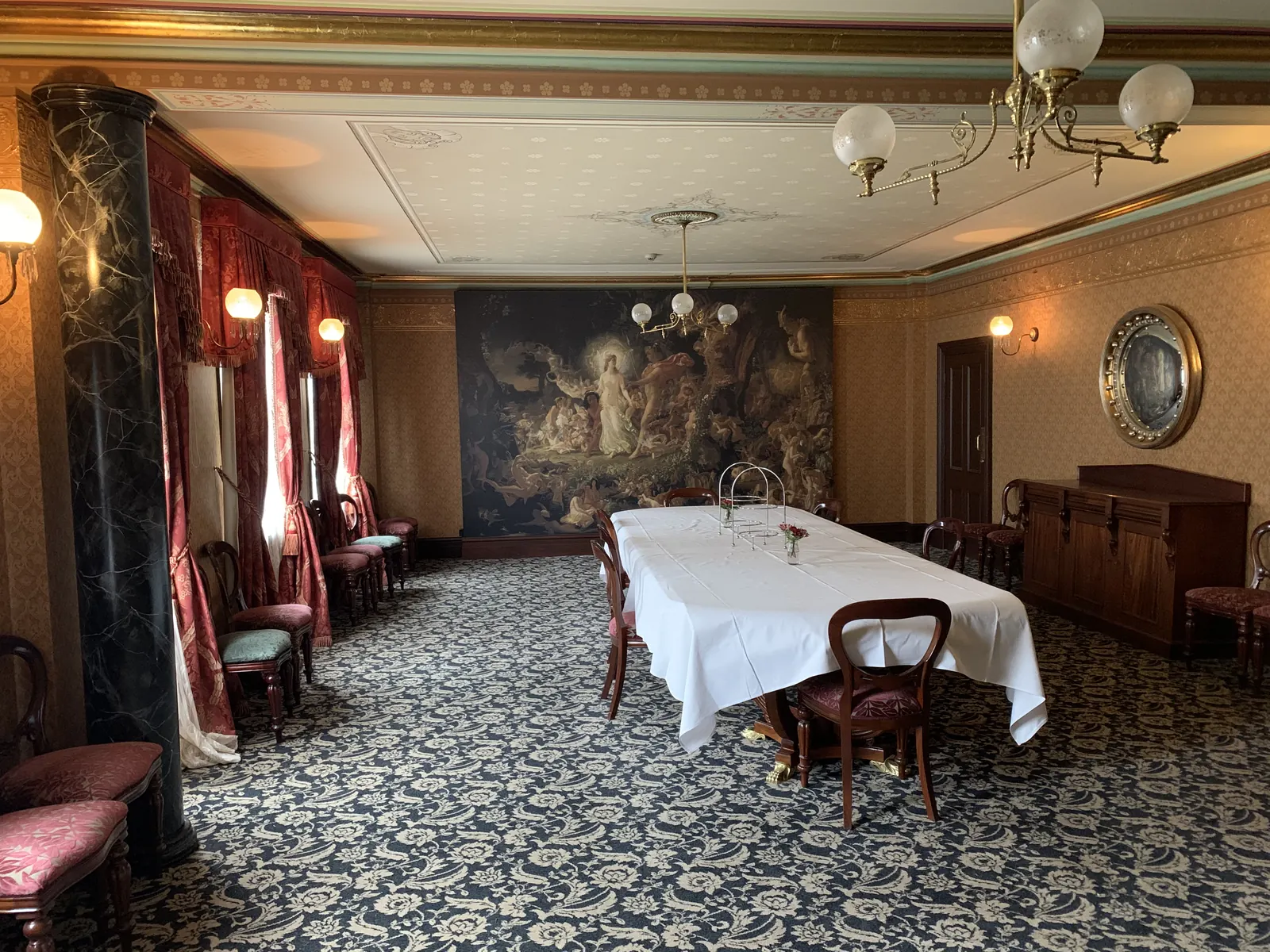 Formal dining room with a large painted mural on the wall