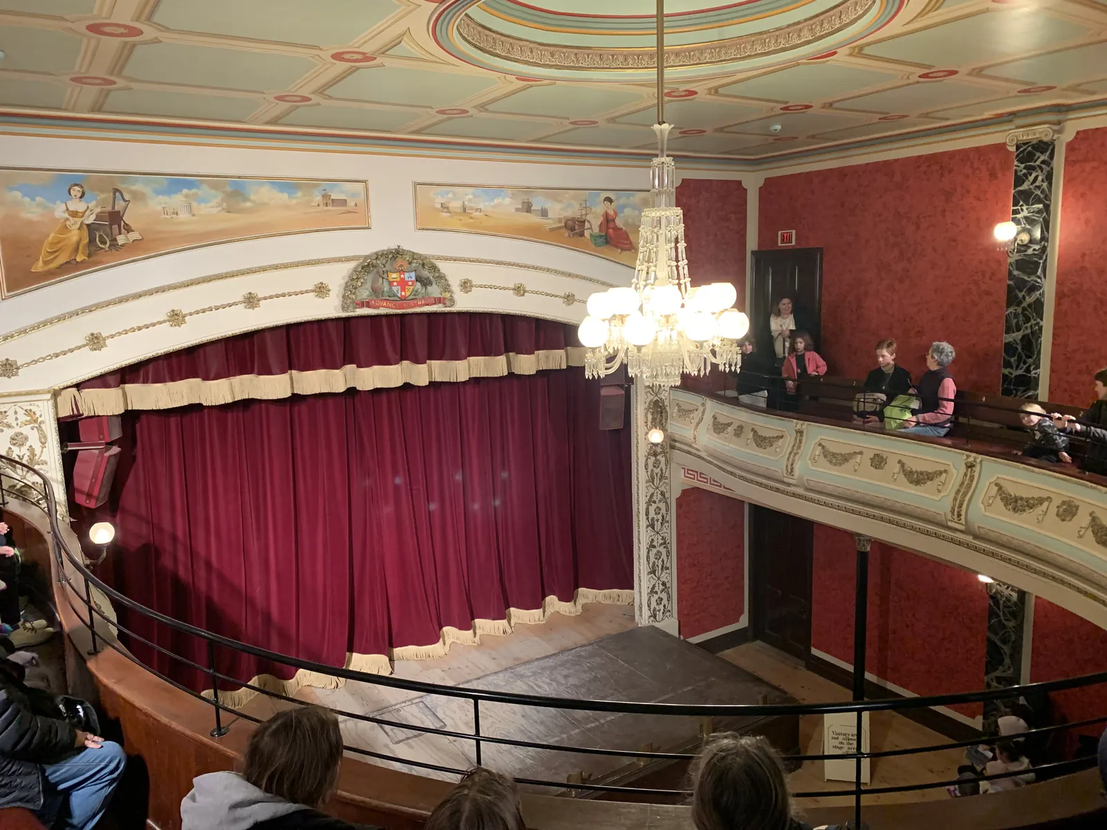 Ornate Victorian theatre interior with chandelier, red curtains and balcony