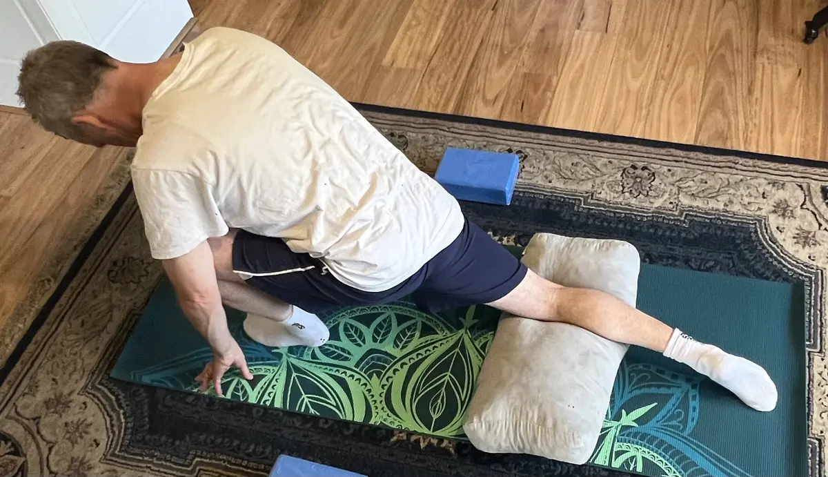 Supported hip stretch on a mat with a cushion